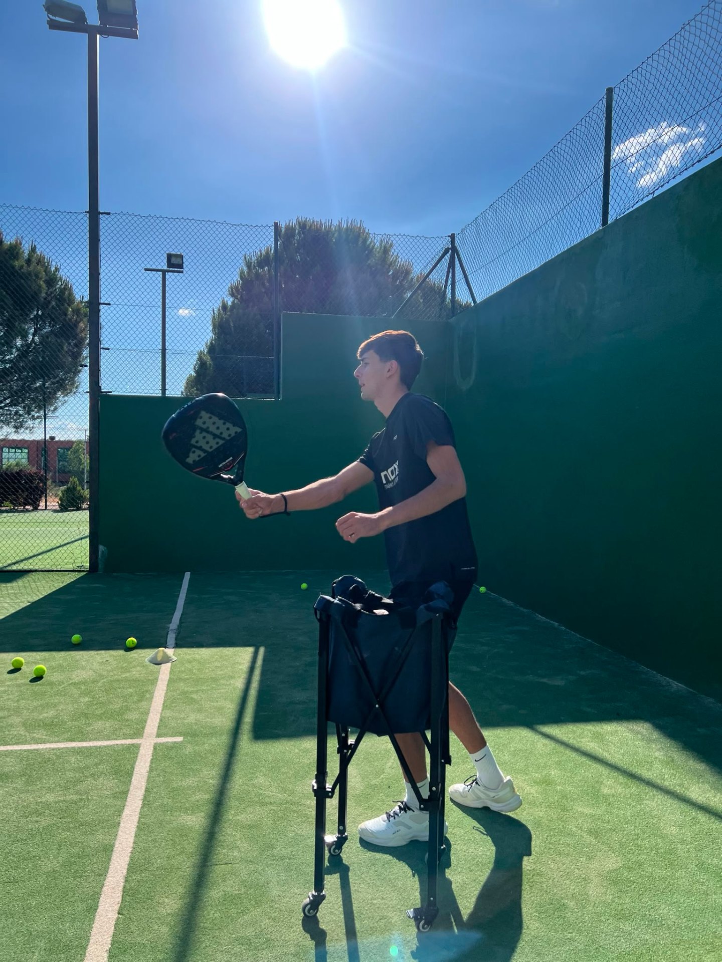 Nacho García entrenando con el carro de bolas en una pista de pádel